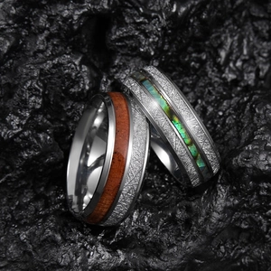 Detail of silver rings with meteorite texture, acacia wood, and abalone shell inlays