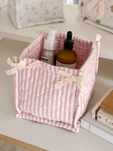 Close-up of pink striped fabric storage basket with lace bow detail for desk decor
