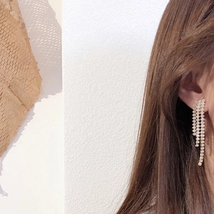 Close-up of elegant long tassel earrings with sparkling rhinestones worn by a model