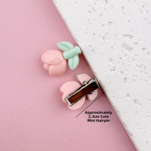 Detail view of mini peach resin hair clip with silver metal snap clip, size approx 2.3cm