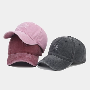 Close-up of three washed cotton baseball caps in pink, burgundy, and dark grey colors