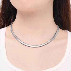 Dettaglio di una collana minimalista in maglia a serpente argento sul collo