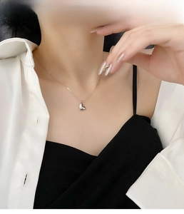 Close-up of minimalist silver heart pendant necklace on a model wearing elegant attire