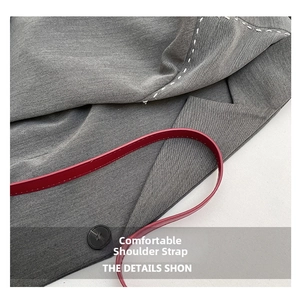 Close-up of grey twill fabric detail with contrast stitching and thin red leather strap