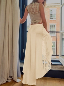 Detailed view of beige satin skirt with elegant lace patchwork and high side slit design