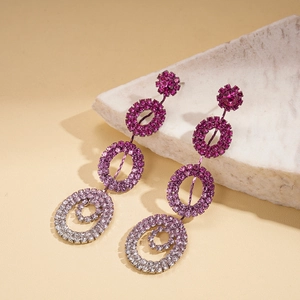 Macro view of geometric flower earrings with pink gradient crystals on marble base