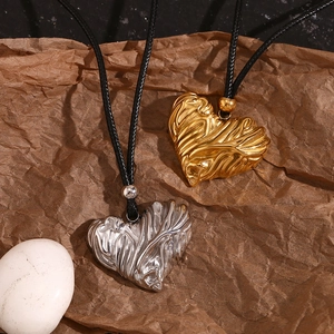 Macro detail of gold and silver heart pendants with lava texture on black cord