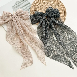 Close-up of bohemian paisley bow hair clips with long streamers in pink and dark green