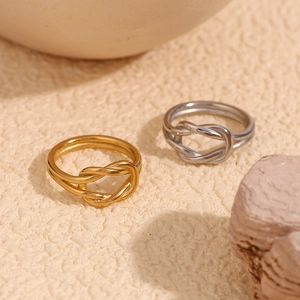 Detailed close-up of intertwined knot rings in gold and silver finish with high polish