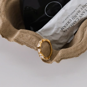 Detail of gold open ring with marquise and round white zircons on craft paper
