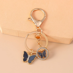 Detail of golden keychain featuring black butterfly and rhinestone encrusted hollow pendant