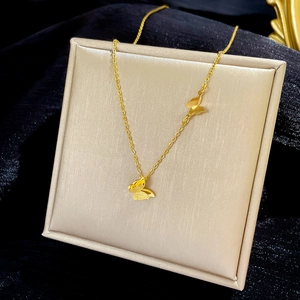 Detail of gold butterfly necklace with matte and polished finish on display cushion