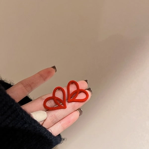 Close-up of red flocked heart-shaped stud earrings with a velvet texture finish