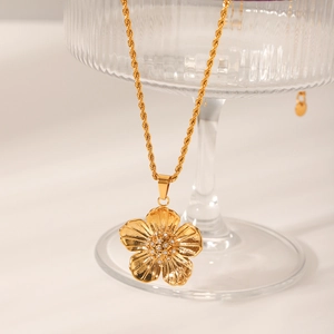 Detail of flower pendant with crystal center on a golden twisted chain necklace