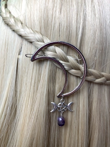 Detail of silver crescent moon hair clip with purple gemstone on braided blonde hair