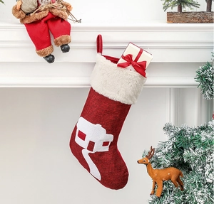 Close-up of red linen Christmas stocking with white house pattern on a mantel