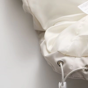 Nahaufnahme der weißen Steppjacke mit glattem Nylonstoff und Kordelzug-Details