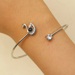 Détail macro du bracelet ouvert cygne argenté avec pierre de projection noire et zircon