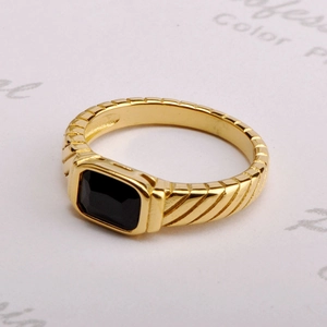 Detailed view of a gold titanium ring with a rectangular black zircon and striped texture