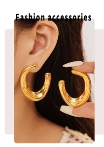Detailed view of large gold U-shaped earrings with irregular arcs worn by a model