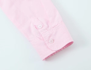 Close-up of pink poplin shirt sleeve cuff featuring two white buttons and fine stitching