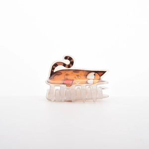 Detail of cute orange cat hair claw clip showing acetate material and funny face pattern