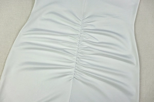 Detailed close-up of vertical ruched texture and soft white fabric on a slim-fit dress