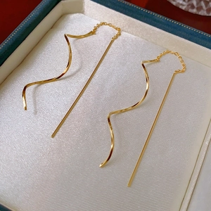 Gros plan détaillé de boucles d'oreilles chaînes dorées sur un écrin en velours bleu