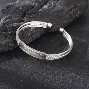 Detail view of double-stranded steel wire braid cuff bracelet on dark rock background