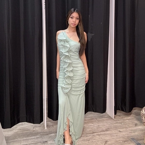 Détail de la robe longue vert clair à une épaule avec volants et fente latérale