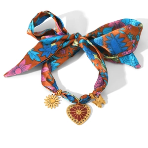 Détail du bracelet ruban floral avec breloques dorées de tournesol, de cœur et de papillon