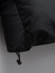 Detail of adjustable drawstring hem with toggle on matte black puffer jacket