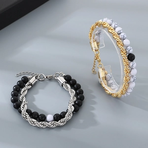 Close-up of gold and silver layered beaded bracelets with matte onyx and marble stones