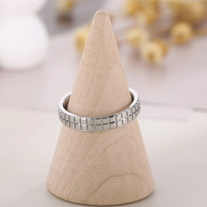 Detailed view of silver stainless steel ring with square grid texture on a wooden stand
