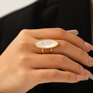 Anello dorato ovale con inserto in conchiglia bianca naturale indossato da donna
