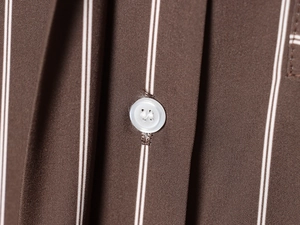 Close-up of a white button on brown and white vertical striped fabric detailing texture