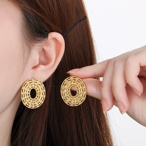 Detail of gold woven oval earrings showing intricate texture and size on a model