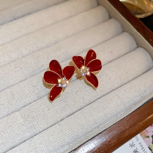 Détail des boucles d'oreilles fleurs en émail rouge foncé avec centre en cristal brillant