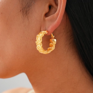 Macro detail of 24k gold-plated geometric wrinkled hoop earrings with woven texture
