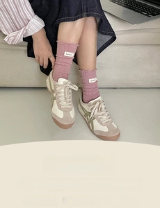 Detail view of pink ruffled socks paired with vintage beige and green sneakers