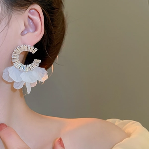 Close-up of model wearing C-shaped earrings with zircon accents and white floral petals