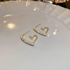 Macro shot of gold-plated irregular heart earrings with sparkling pavé zircons on ceramic
