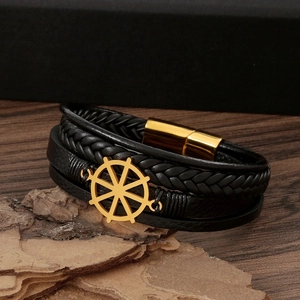 Detailed shot of nautical leather bracelet with golden rudder charm and magnetic clasp