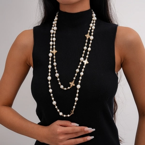 Gros plan d'un élégant collier de perles à deux rangs avec pendentifs croix dorés sur noir