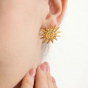 Gros plan de boucles d'oreilles soleil en or 18k avec texture spirale sur le mannequin