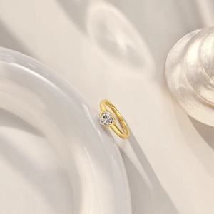 Macro shot of heart-shaped zircon ring with gold band on a decorative ceramic shell plate