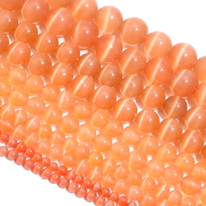 Detailed view of orange cat eye stone round beads in various sizes for DIY jewelry