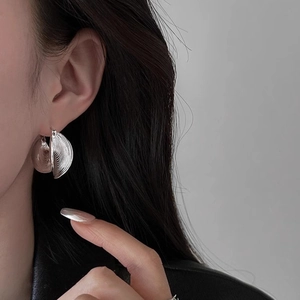 Chic silver metallic hoop earrings with shell texture shown on a female model