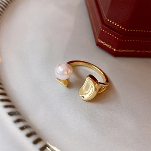 Detailed macro of gold plated open ring featuring a white pearl and irregular organic metal