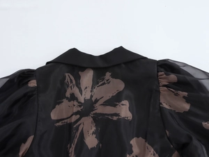 Détail du col de chemise et manche bouffante plissée sur robe noire en organza fleuri